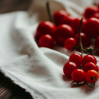 Cherry tomatoes on the vine, resting on a white cloth.
