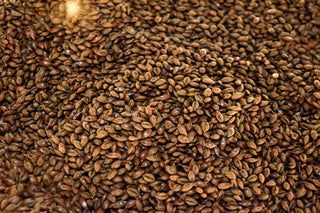 A close-up of a large quantity of small brown seeds, densely packed together, showcasing their smooth and uniform texture. The seeds create a rich, earthy pattern, emphasizing their natural, organic appearance.