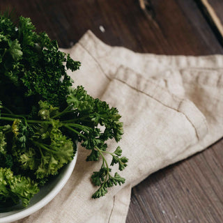 A bowl of fresh Italian parsley on a linen napkin, highlighting its lush, green leaves.